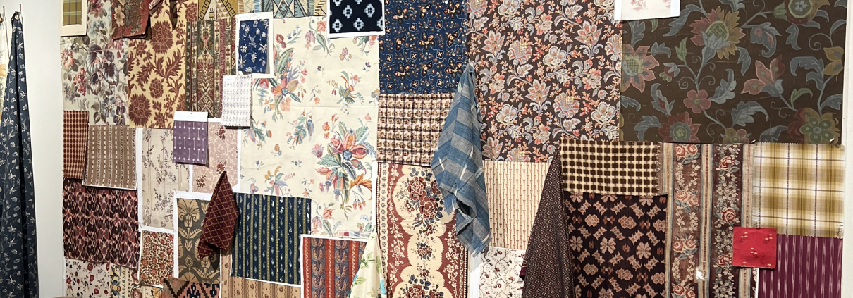 Showroom display at High Point Market Spring 2026 featuring warm brown tones, carved wood furniture, and mixed fabric upholstery
