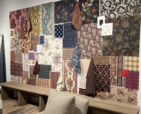 Showroom display at High Point Market Spring 2026 featuring warm brown tones, carved wood furniture, and mixed fabric upholstery